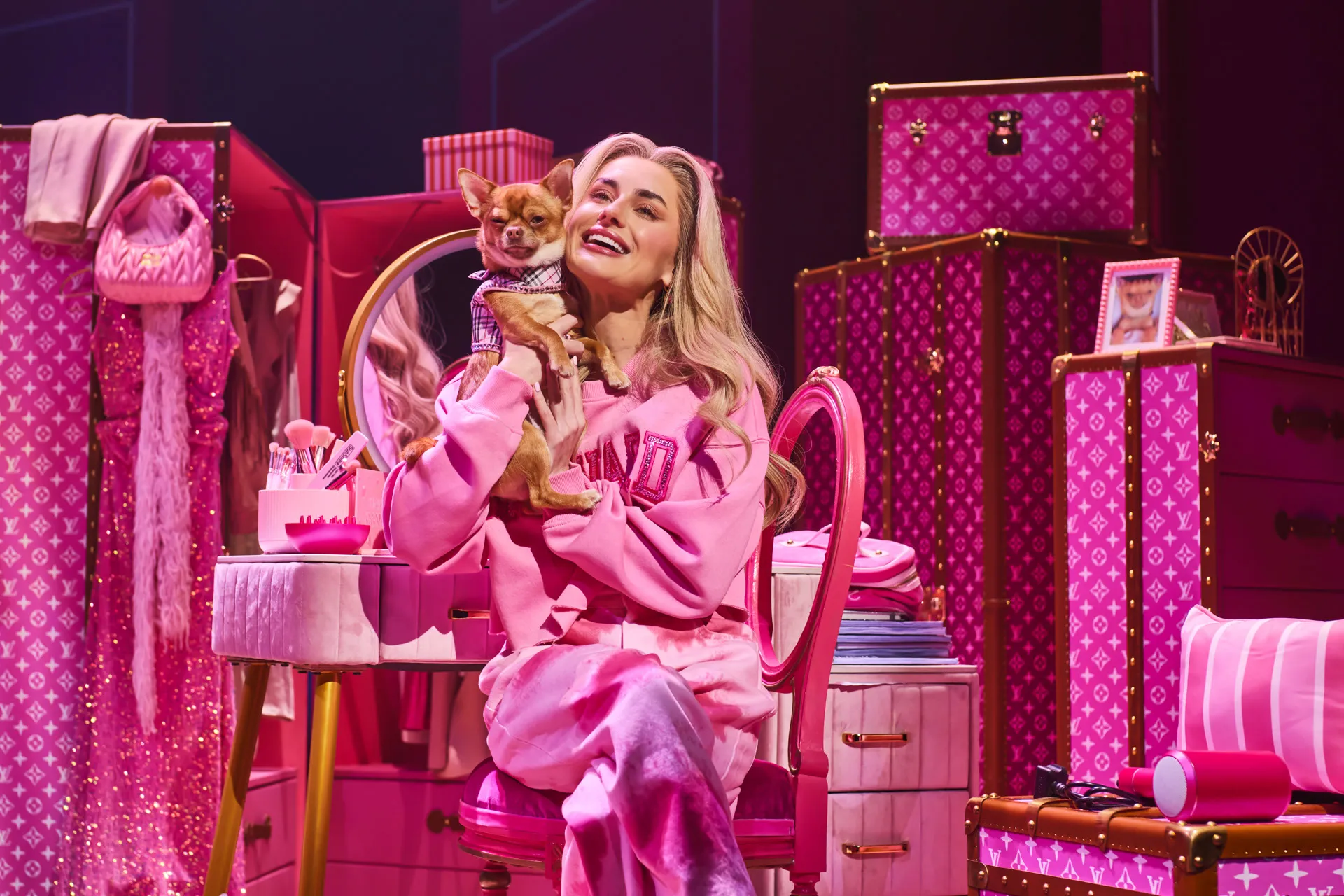 Amber Davies as Elle Woods holds Bruiser the chihuahua in her all-pink dressing room in Legally Blonde The Musical